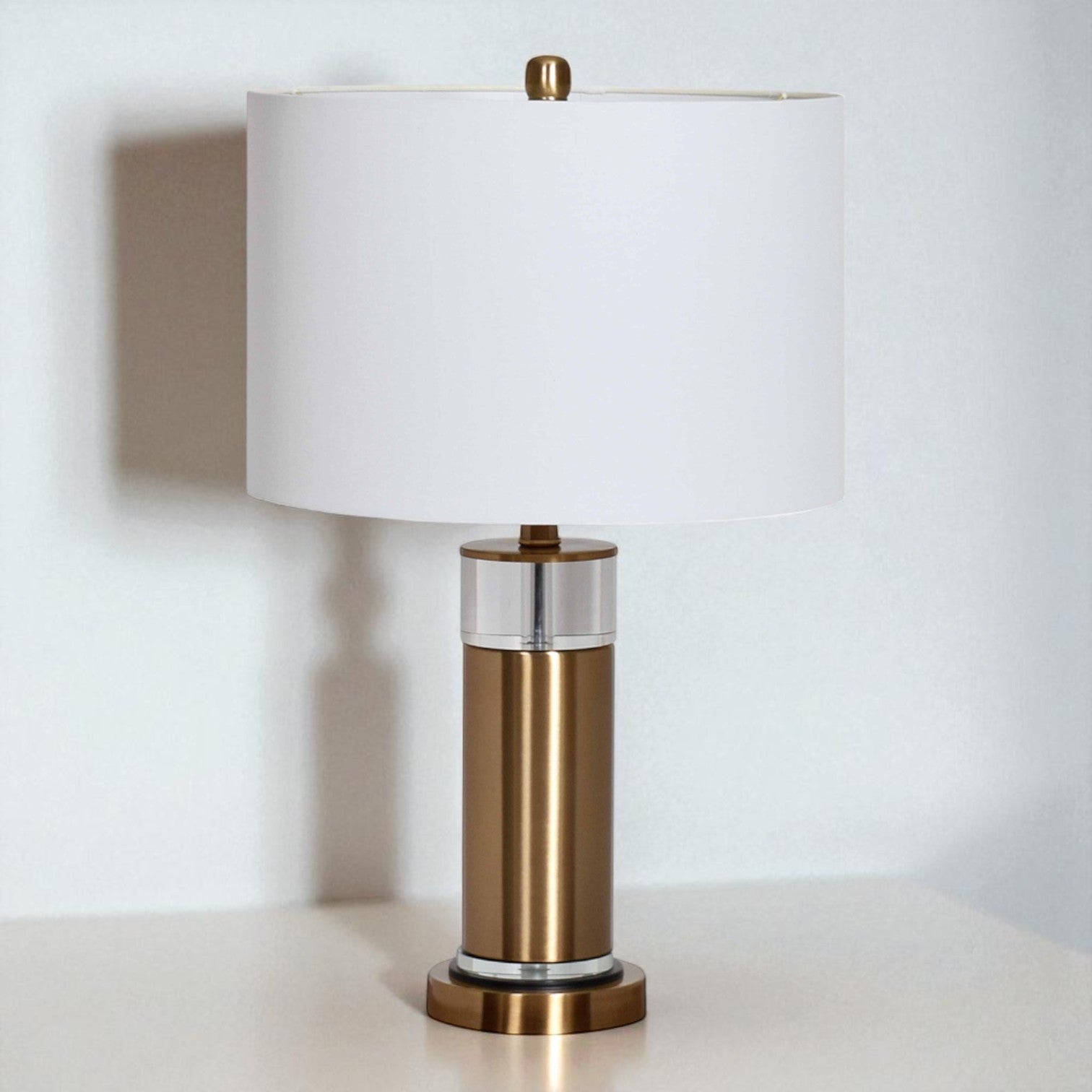 Table lamp with bronze base and white shade on a light surface.