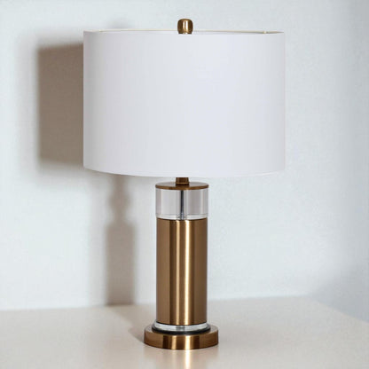 Table lamp with bronze base and white shade on a light surface.