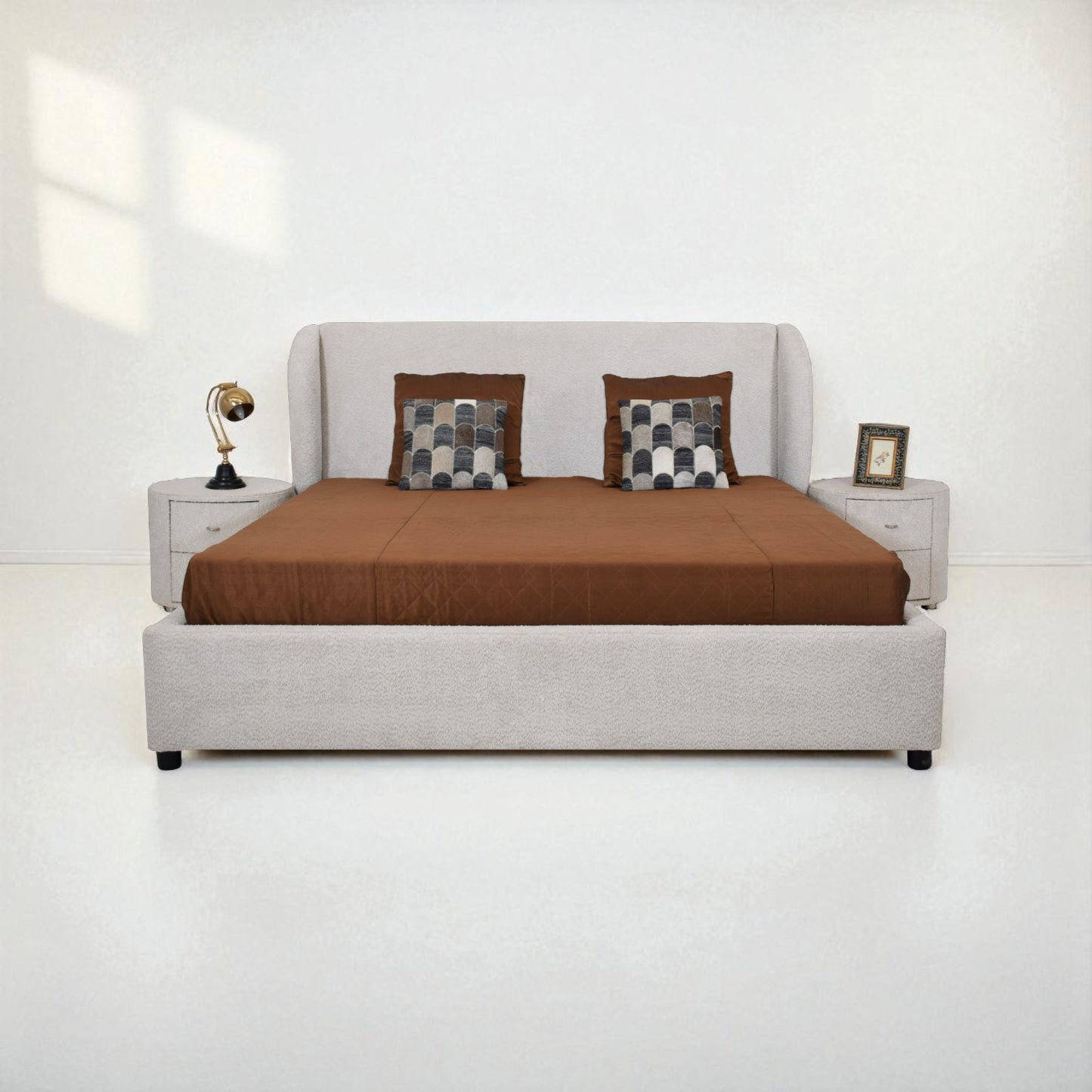 Gray upholstered bed with brown bedding and checkered pillows on a white background