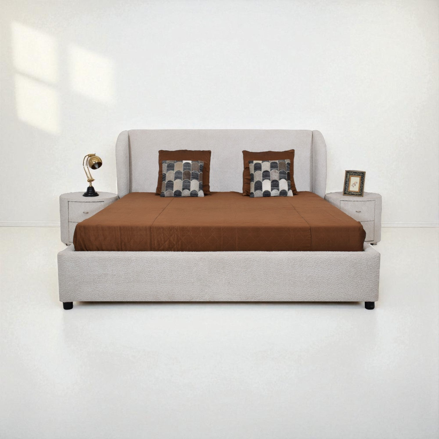 Gray upholstered bed with brown bedding and checkered pillows on a white background