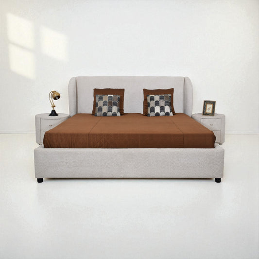 Gray upholstered bed with brown bedding and checkered pillows on a white background