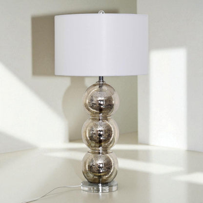Table lamp with a decorative base and white shade on a light surface.