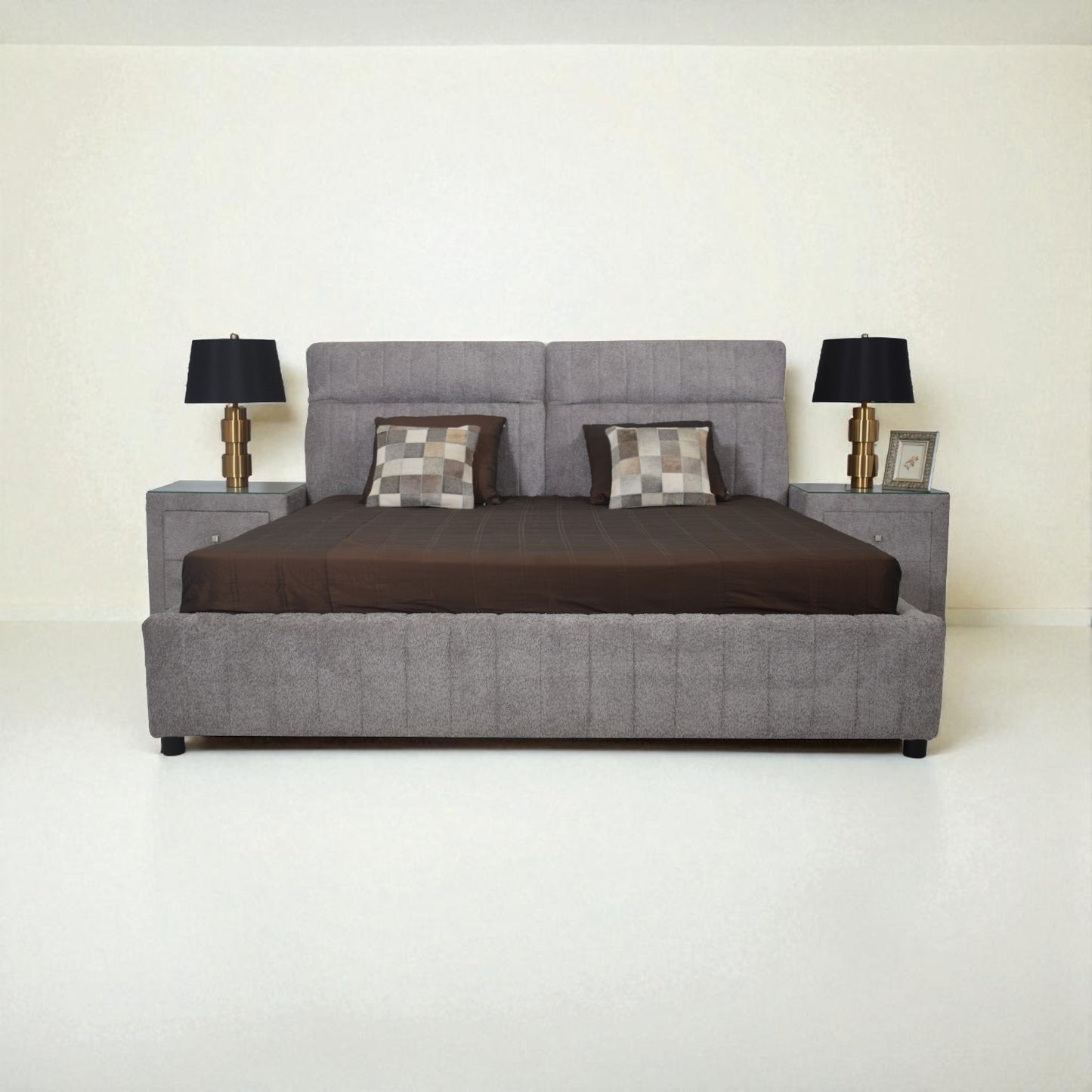 Gray upholstered bed with brown bedding and two lamps on a white background