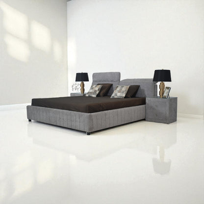 Gray upholstered bed with dark bedding in a minimalistic room.