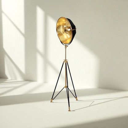 Vintage-style floor lamp with gold shade and black tripod base on a white background