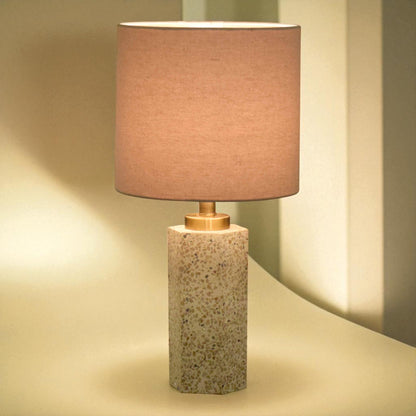Table lamp with a textured base and pinkish-brown shade on a neutral background