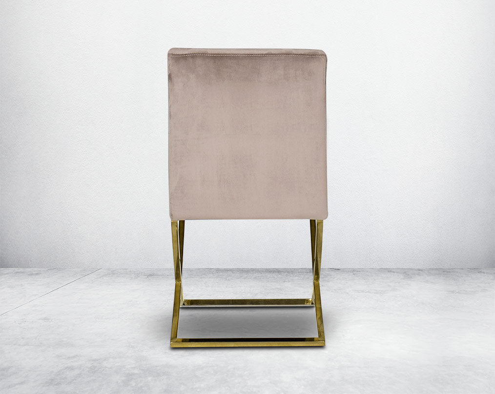 Dining chair with back  upholstered in fabric with gold plated stainless steel legs in a cross design.