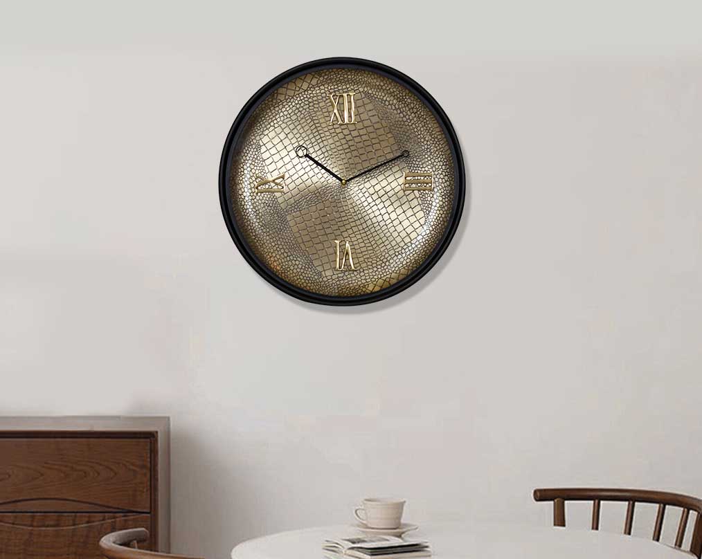 Round wall clock in croc etched design with a matt antique brass finish in black polish with table and chair 